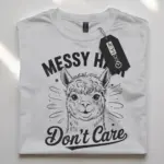 white flatlay alpaca tee with messy hair dont care text